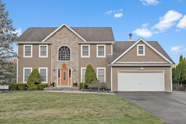 colonial home featuring a front yard and a garage