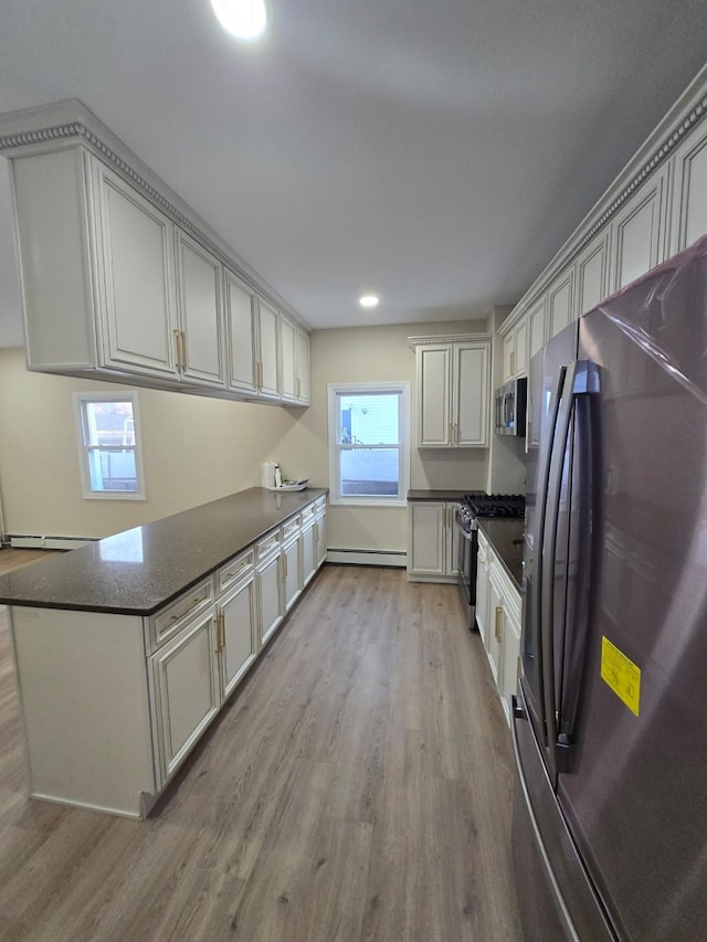 kitchen with kitchen peninsula, plenty of natural light, light hardwood / wood-style floors, and appliances with stainless steel finishes