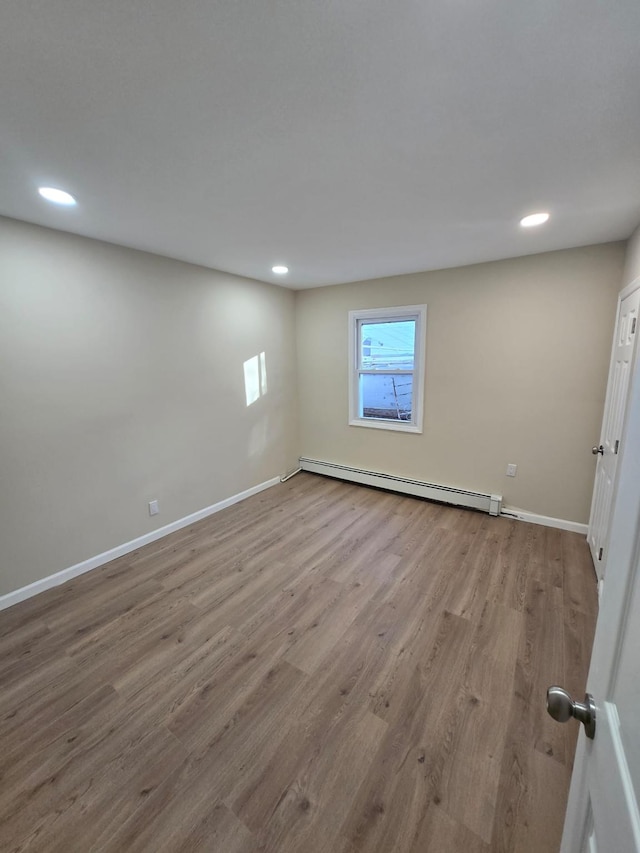 basement featuring light hardwood / wood-style flooring and a baseboard radiator