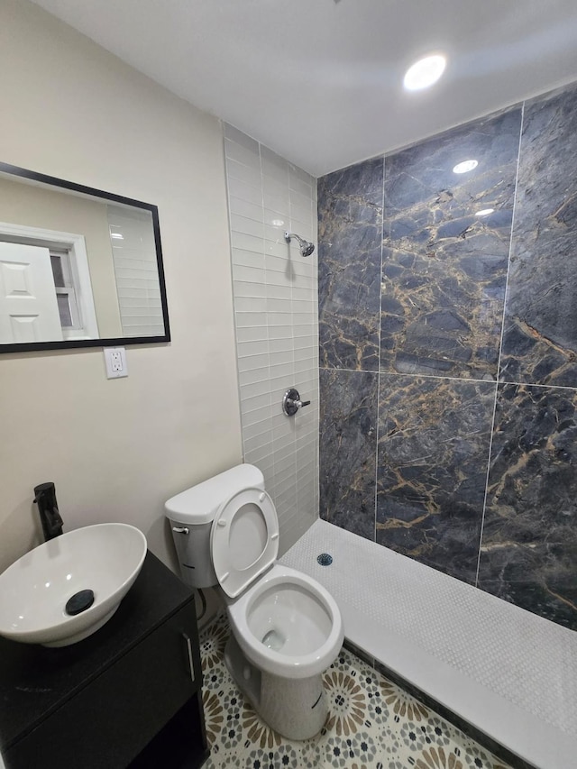 bathroom featuring a tile shower, tile patterned floors, vanity, and toilet