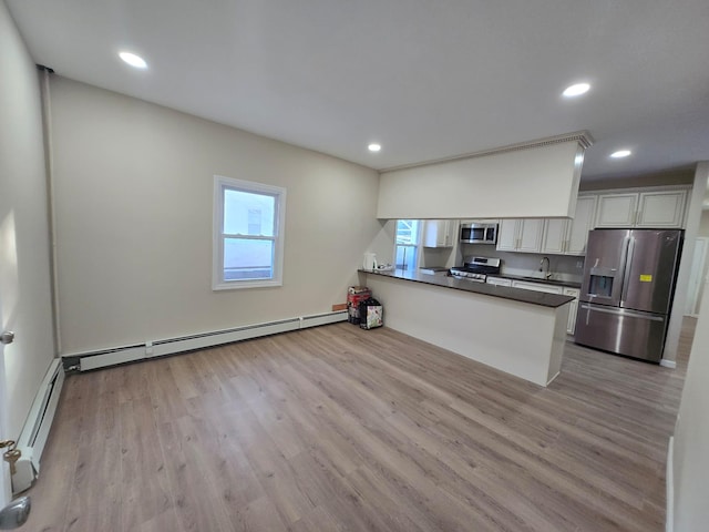 kitchen with kitchen peninsula, a wealth of natural light, stainless steel appliances, and baseboard heating