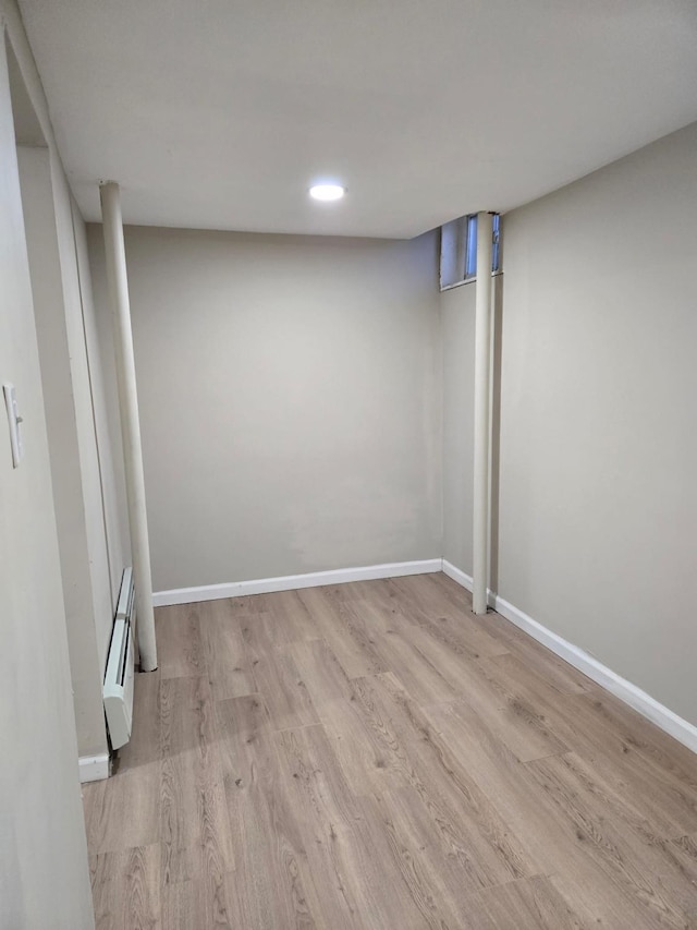 unfurnished room featuring light wood-type flooring and a baseboard heating unit