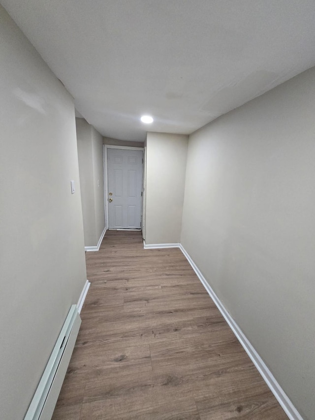 corridor with light hardwood / wood-style flooring and a baseboard heating unit