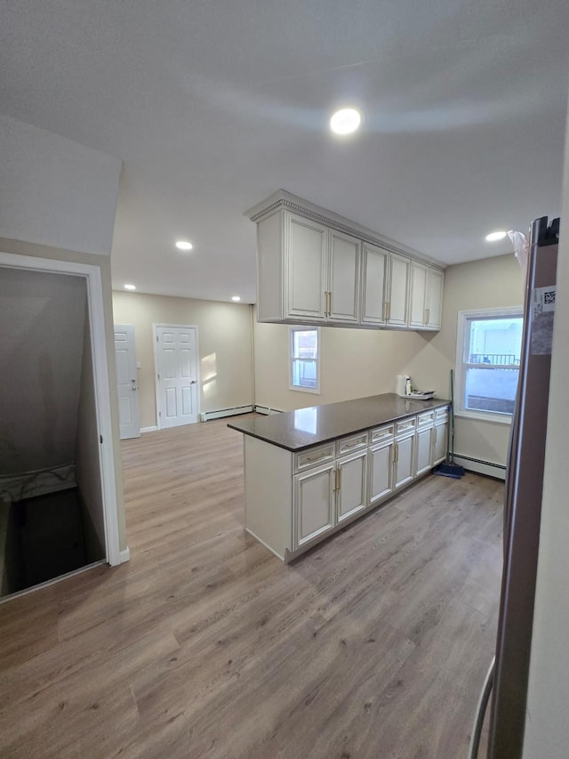 kitchen with stainless steel refrigerator, kitchen peninsula, light hardwood / wood-style floors, and baseboard heating