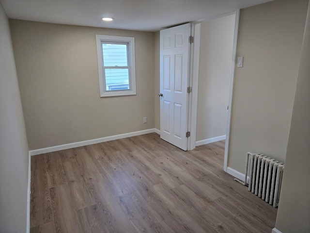 unfurnished room with light wood-type flooring and radiator