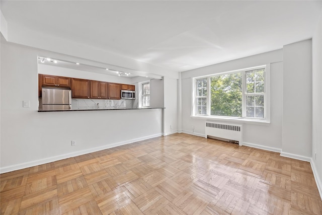 unfurnished living room with radiator heating unit and light parquet floors