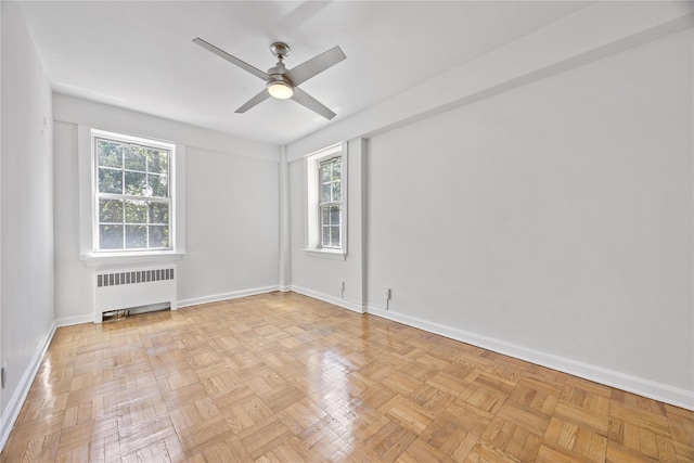 spare room with ceiling fan, radiator, and light parquet flooring