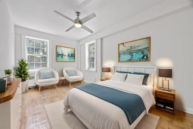 bedroom featuring multiple windows, radiator, light parquet flooring, and ceiling fan