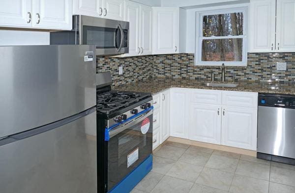 kitchen with white cabinets, decorative backsplash, sink, and stainless steel appliances