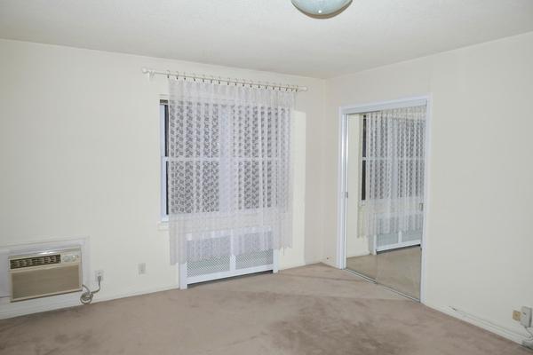 carpeted empty room featuring a wall mounted air conditioner and radiator heating unit