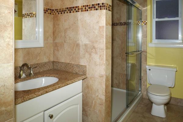 bathroom with vanity, toilet, and a shower with door