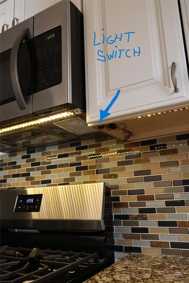 details with gas stove, tasteful backsplash, white cabinets, and dark stone counters