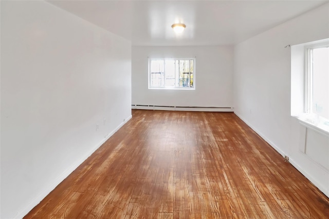 empty room featuring wood-type flooring and a baseboard radiator