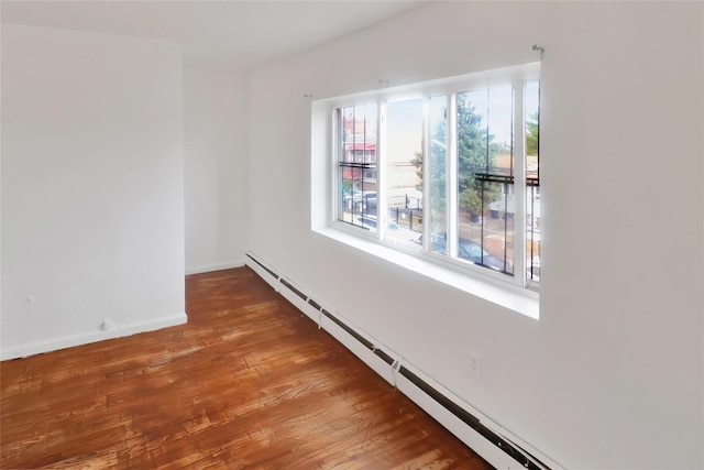 empty room featuring hardwood / wood-style floors and a baseboard radiator