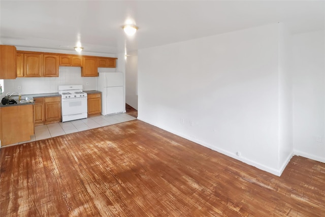 kitchen with light hardwood / wood-style floors, white appliances, and backsplash