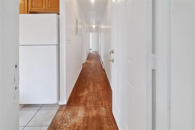 corridor with light wood-type flooring and baseboard heating