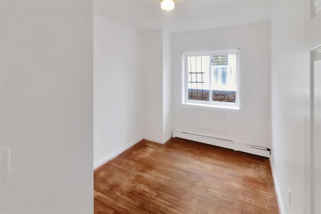 empty room featuring hardwood / wood-style floors and a baseboard radiator