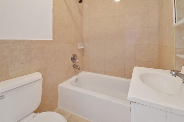 full bathroom featuring tiled shower / bath, vanity, tile walls, and toilet