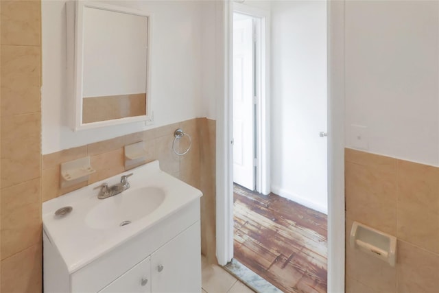 bathroom with hardwood / wood-style flooring, vanity, and tile walls