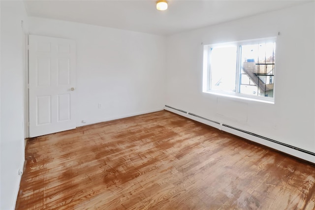 unfurnished room with a baseboard radiator and hardwood / wood-style flooring