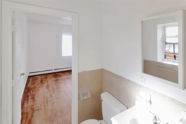 bathroom featuring sink, a baseboard heating unit, wood-type flooring, toilet, and tile walls