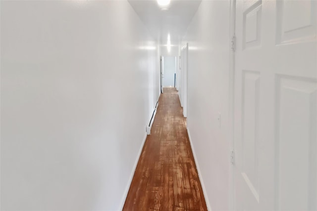 corridor with baseboard heating and wood-type flooring