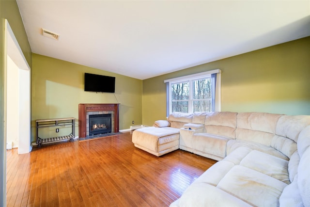 living room with wood-type flooring and a tile fireplace