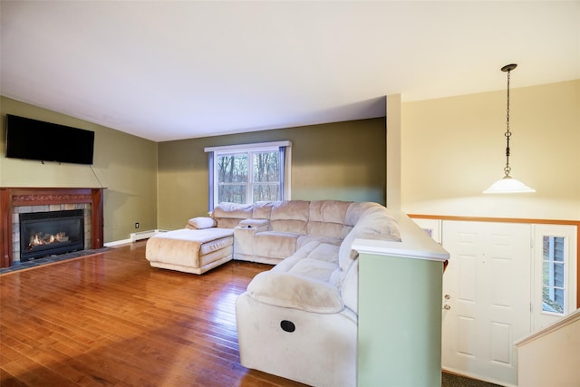 living room featuring hardwood / wood-style floors, baseboard heating, and a tile fireplace