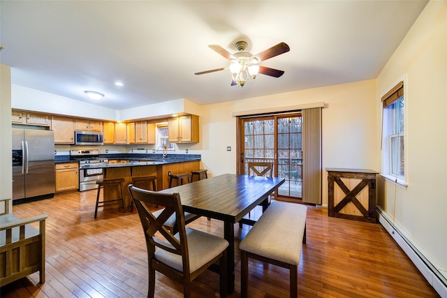 dining area featuring lofted ceiling, a baseboard heating unit, sink, ceiling fan, and wood-type flooring