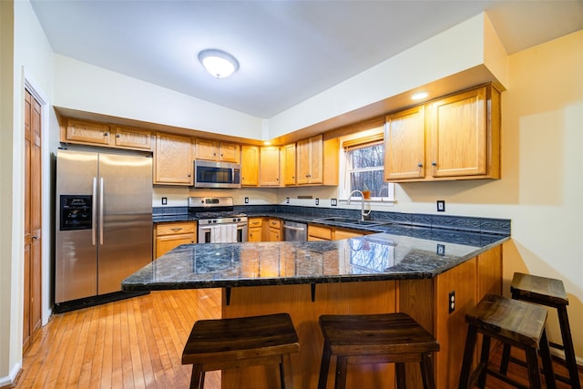 kitchen featuring a kitchen bar, kitchen peninsula, sink, and appliances with stainless steel finishes