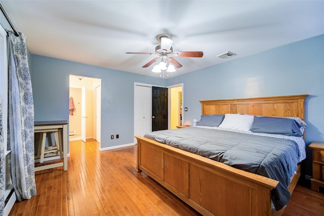 bedroom with ceiling fan, light wood-type flooring, and baseboard heating