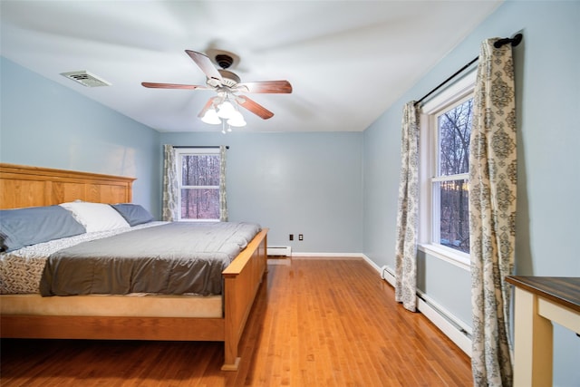 bedroom with ceiling fan, a baseboard radiator, and light hardwood / wood-style flooring