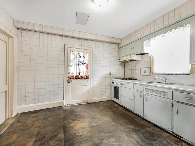 kitchen featuring white oven, sink, tile walls, and stainless steel gas cooktop