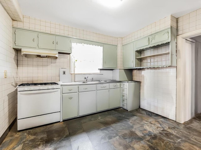 kitchen with white gas range, sink, and tile walls