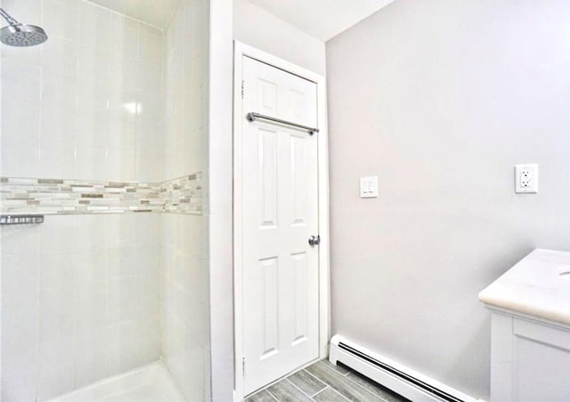 bathroom with vanity, a tile shower, and a baseboard radiator