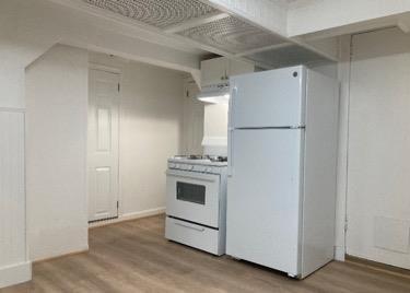 kitchen with white appliances, ventilation hood, and hardwood / wood-style floors