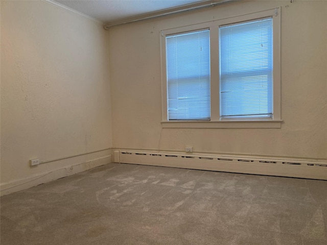 carpeted empty room featuring ornamental molding and baseboard heating