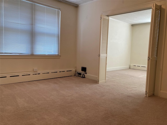 carpeted empty room featuring a textured ceiling, baseboard heating, and ornamental molding