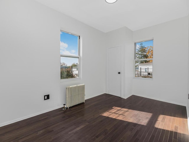 empty room featuring dark hardwood / wood-style floors and radiator heating unit