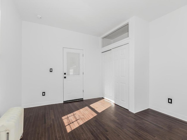 spare room with radiator heating unit and dark hardwood / wood-style floors