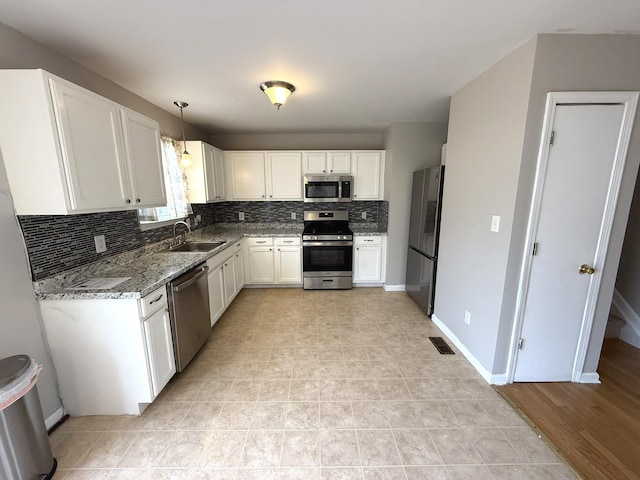 kitchen with backsplash, stainless steel appliances, sink, pendant lighting, and white cabinetry