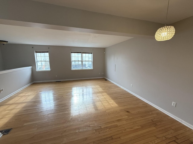 empty room with a chandelier and light hardwood / wood-style floors