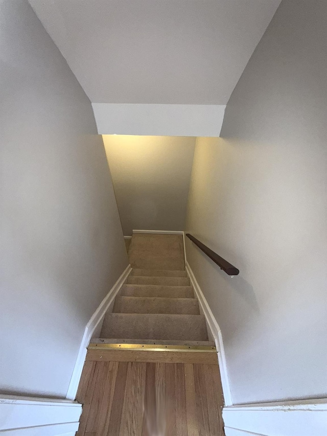 stairway with hardwood / wood-style floors and vaulted ceiling