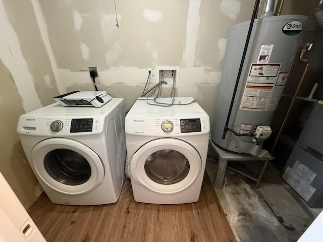 laundry area featuring water heater, washer and clothes dryer, and hardwood / wood-style flooring