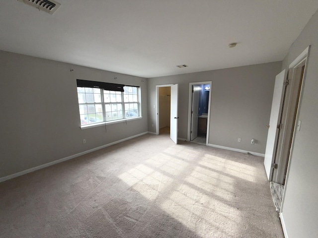 unfurnished bedroom featuring light colored carpet and connected bathroom