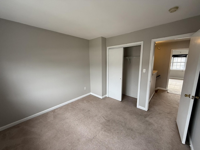 unfurnished bedroom with light colored carpet and a closet