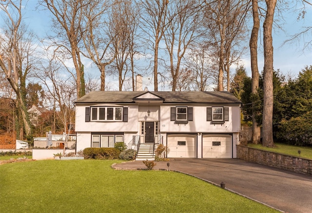 bi-level home featuring driveway, stucco siding, a garage, and a front yard