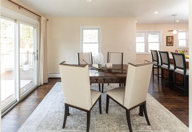 dining area with dark wood-type flooring, baseboard heating, and a healthy amount of sunlight