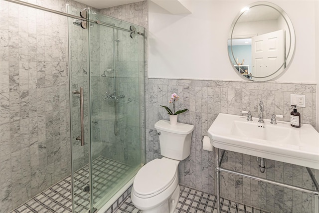 full bathroom with a stall shower, wainscoting, toilet, a sink, and tile walls