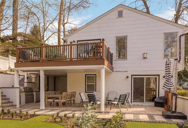 rear view of house featuring stairs, a patio, an outdoor kitchen, and fence